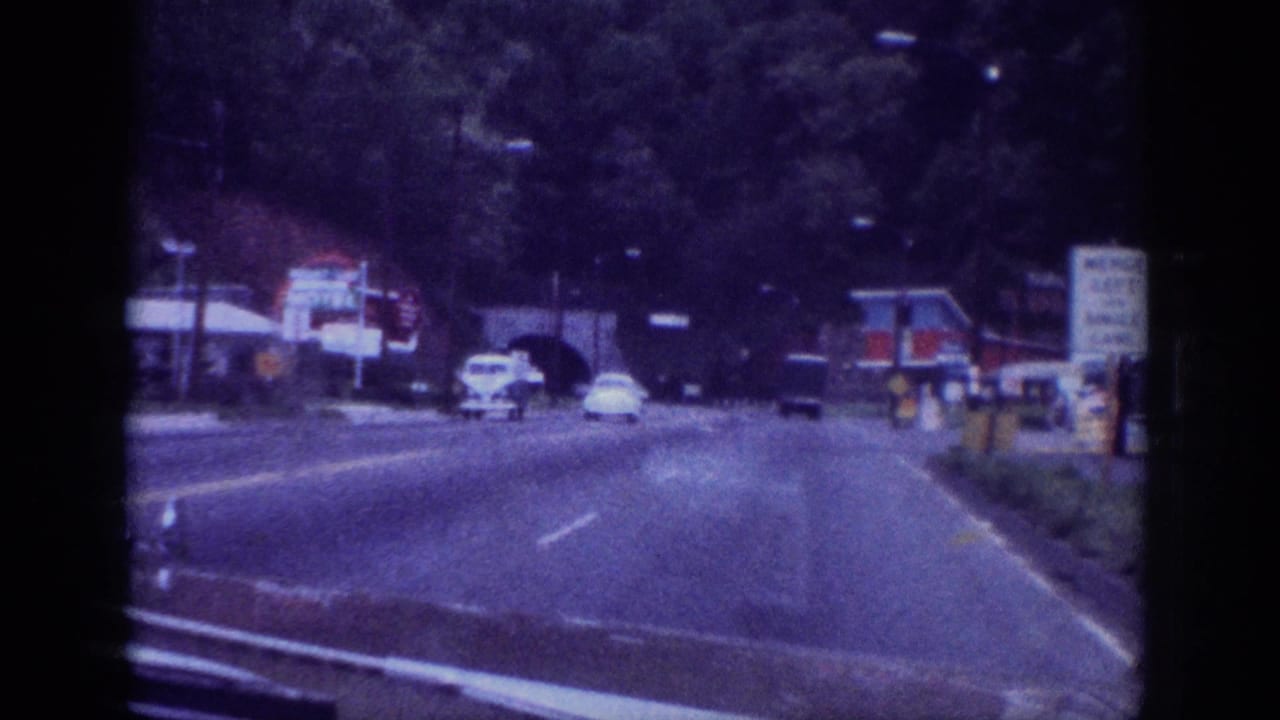 1963 Memphis, Tennessee road scene filmed from a moving car, showing early 1960s automobiles and a commercial roadside strip on aged 8mm film.