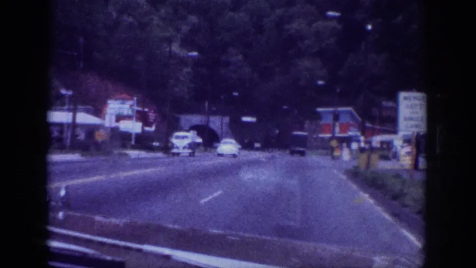 1963 Memphis, Tennessee road scene filmed from a moving car, showing early 1960s automobiles and a commercial roadside strip on aged 8mm film.