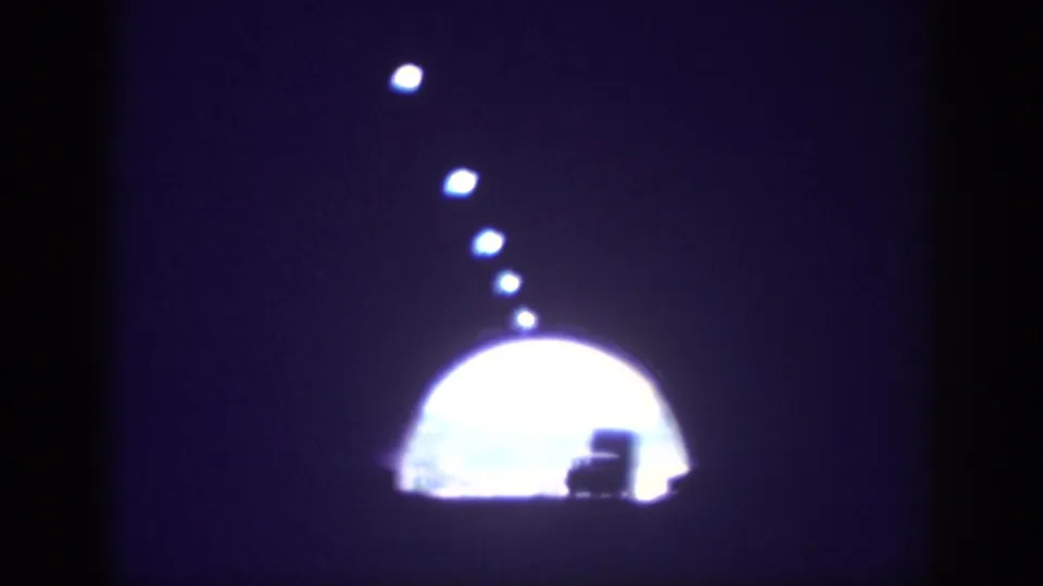 8mm home movie frame circa 1963 approaching tunnel exit, bright arched opening in the distance with a small vehicle silhouette and overhead lights trailing away.