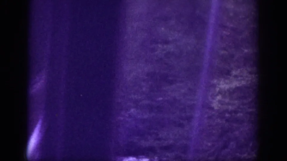 Final river-crossing frame with vertical film flare, forested bank, and deep purple color shift characteristic of deteriorated 8mm stock, circa 1963 Memphis area.