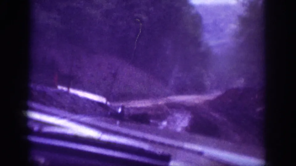 8mm home movie showing chrome vehicle door and window trim with a winding dirt road through wooded area, circa 1963 American South.