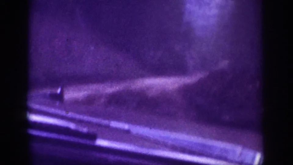 8mm home movie closing frame showing dashboard chrome and a brightened windshield view of a dirt road through trees, circa 1963.