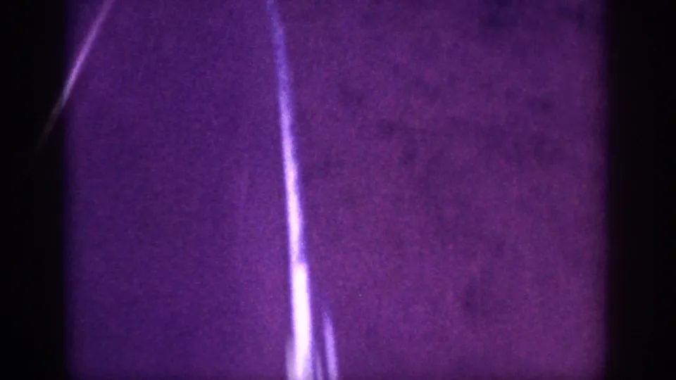 Closing 8mm frame, c.1963, Memphis area — diagonal bright line persists over dark dirt ground as scene ends, deep purple color cast and grain throughout.