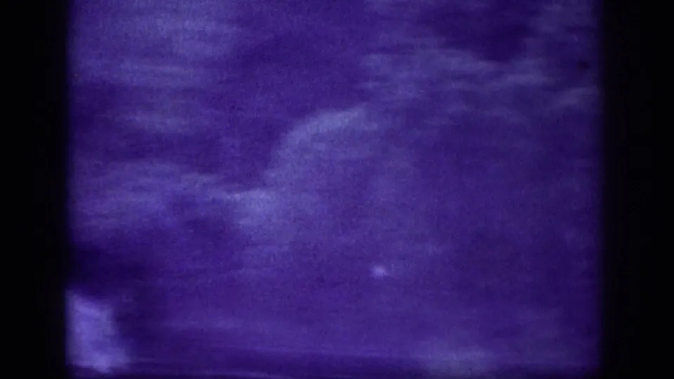 Final 8mm frame from 1963 — camera tilted or shaken toward the sky, motion-blurred storm clouds in deep purple as the storm intensifies.