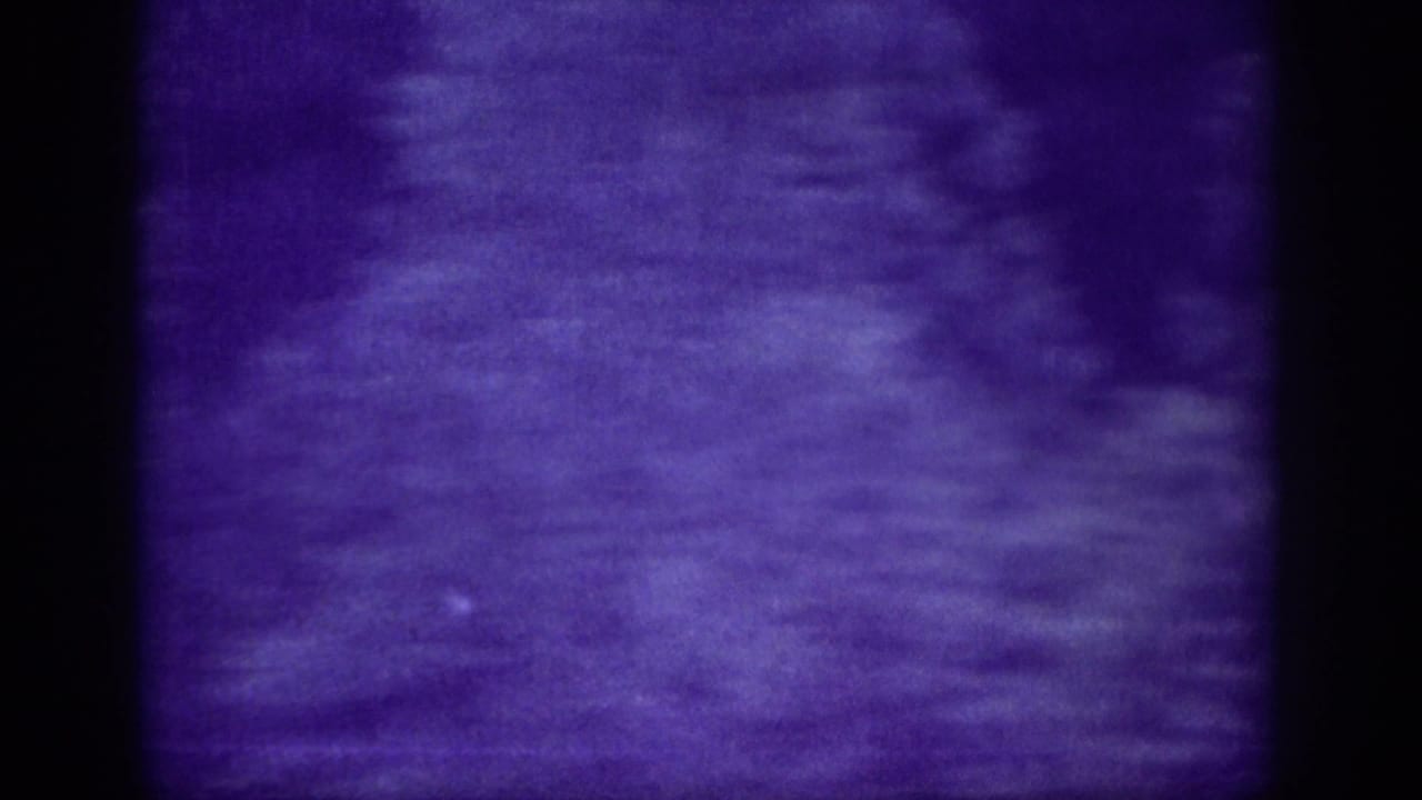 Soft, purple-blue 8mm frame from the Memphis driving clip with heavy motion blur, dark film borders, and only indistinct roadside shapes visible.