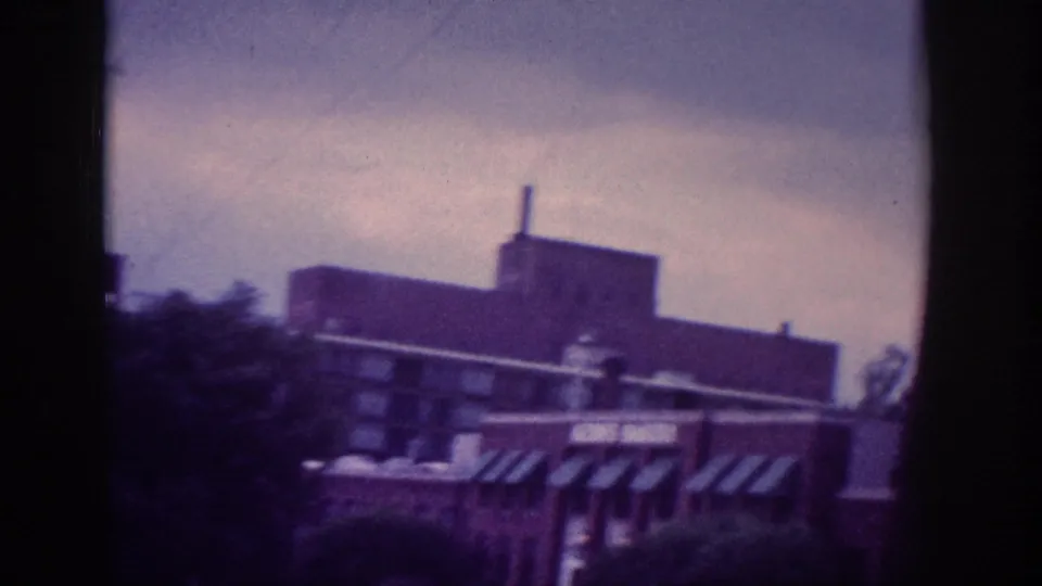 Multi-story brick commercial building with striped awnings, Memphis Tennessee area, circa 1963, heavy purple dye-fade cast, 8mm.
