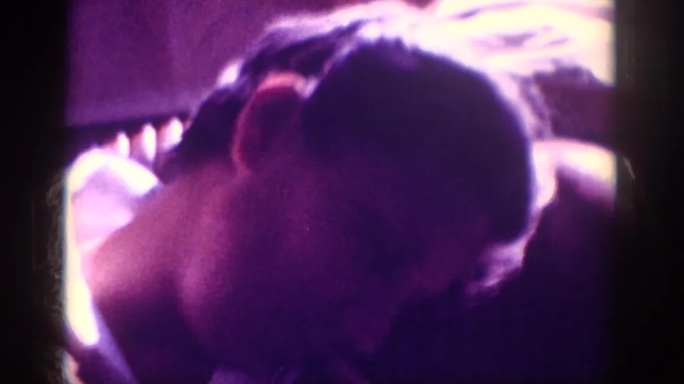 Overhead view of a man's bowed head in a magenta-shifted 8mm home movie frame, metadata-attributed to Memphis, Tennessee, circa 1963.