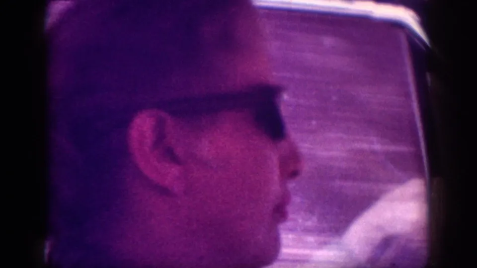 Side-profile close-up of a man in dark-framed sunglasses near what appears to be a vehicle window, in heavily magenta-shifted 8mm footage, metadata-attributed to Memphis, Tennessee, circa 1963.