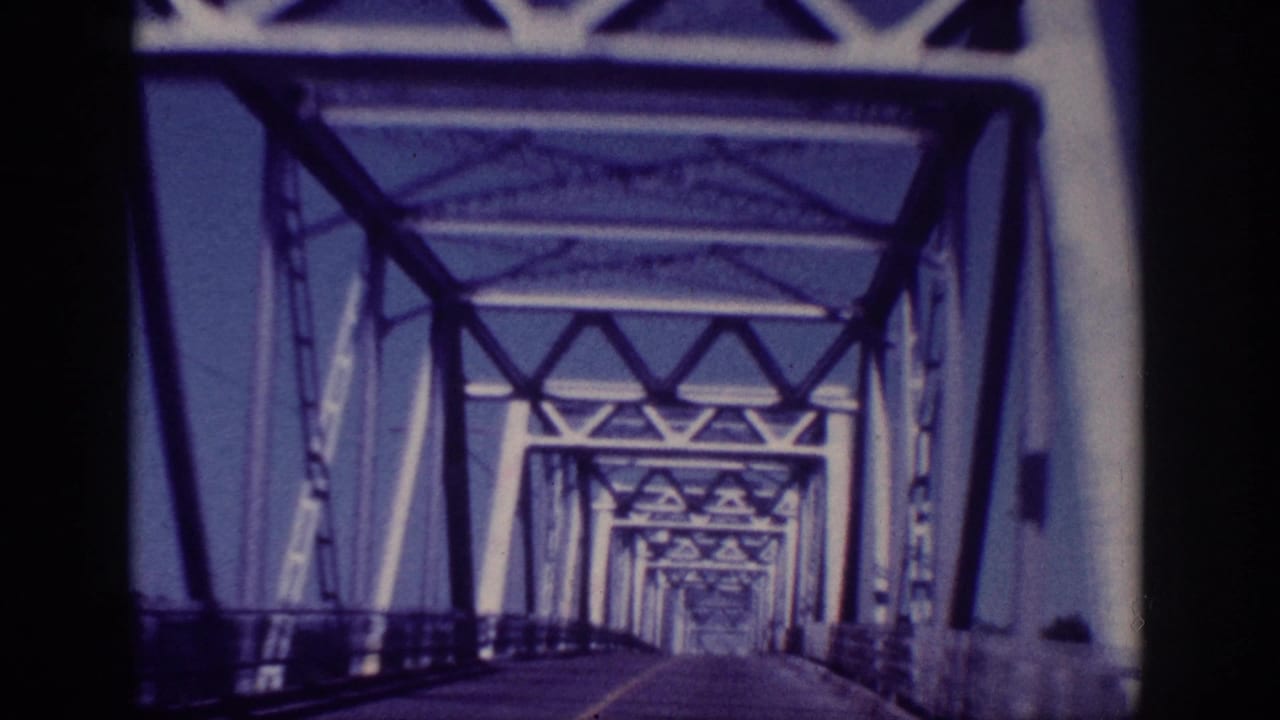 1963 Memphis vehicle POV moving inside a steel truss bridge, with repeating triangular overhead supports and side railings.