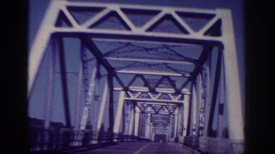 1963 Memphis vehicle POV continuing through the steel truss bridge, with repeating portals receding down the roadway.