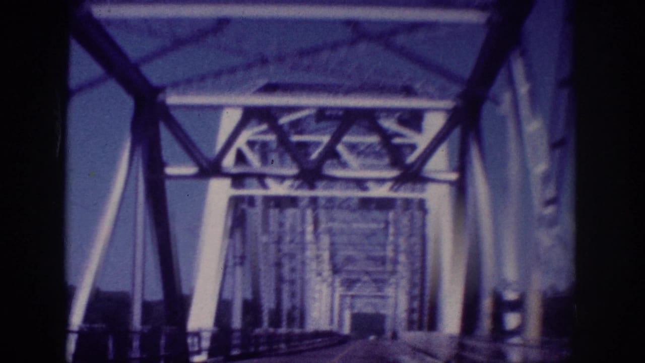 Roadway continues through a steel truss bridge with metal framework receding ahead.