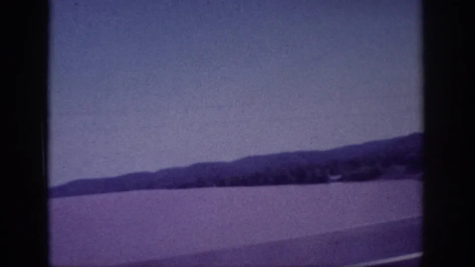 1963 8mm home-movie view near Memphis showing water, distant hills, and a muted sky through soft film grain.
