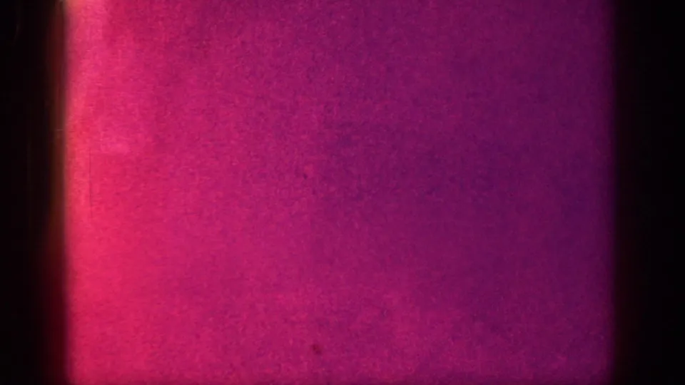 8mm film transition frame showing an intense magenta-red color wash with darkened vignette edges, consistent with a shutter or scene-break between shots