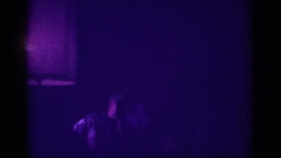 Dim 8mm frame shows a silhouetted person in the foreground and what appears to be a doorway or lit panel at upper left, in a club interior, Memphis 1963.