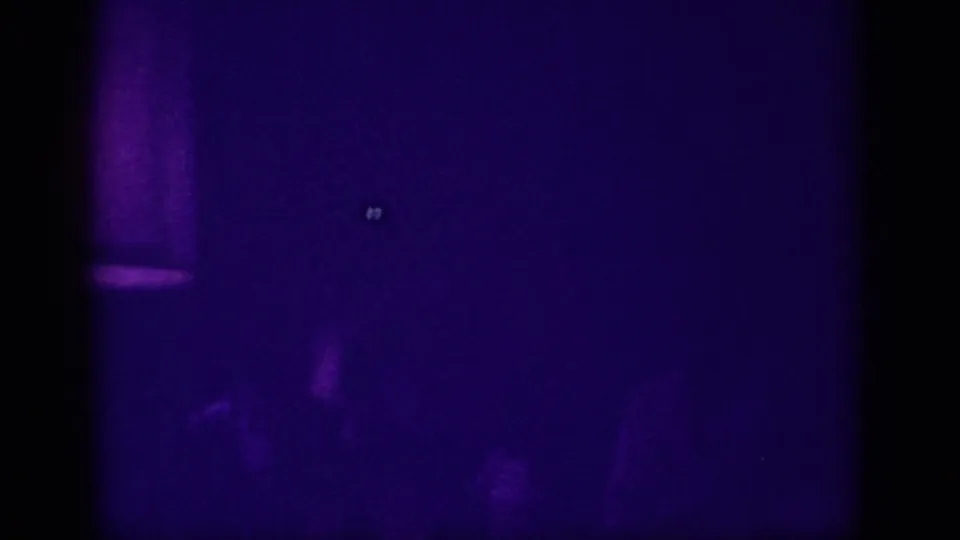 Barely visible silhouetted figure against deep purple darkness in a club interior, with a faint bright point, 8mm footage Memphis 1963.