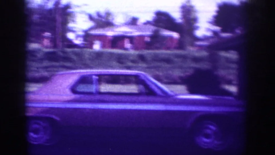 Classic 1960s American sedan in a residential driveway with red brick ranch house and mature trees across the street, Memphis Tennessee circa 1963.
