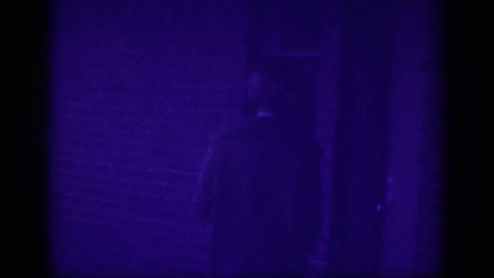 Severely underexposed or transitional frame from an 8mm home movie, showing only a faint silhouette in a deep purple monochrome field, Memphis circa 1963.