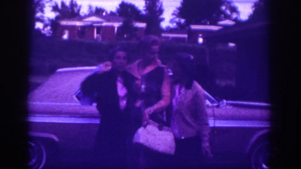 Three women posing in front of a full-size 1960s American sedan with a brick-house suburban streetscape visible behind, possibly Memphis, Tennessee, circa 1963.