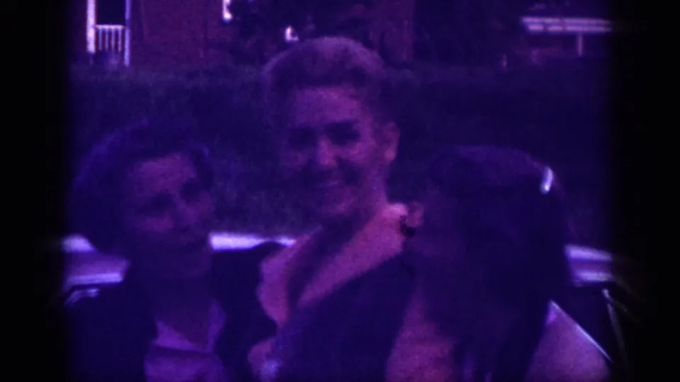 Two women smiling warmly together in close frame outdoors, suburban Memphis, Tennessee, circa 1963; candid moment on aged 8mm home-movie film.