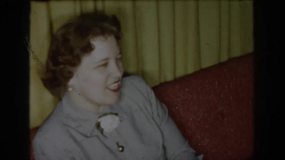1965 Saint Louis home-movie frame showing the woman smiling as she turns slightly toward the camera.