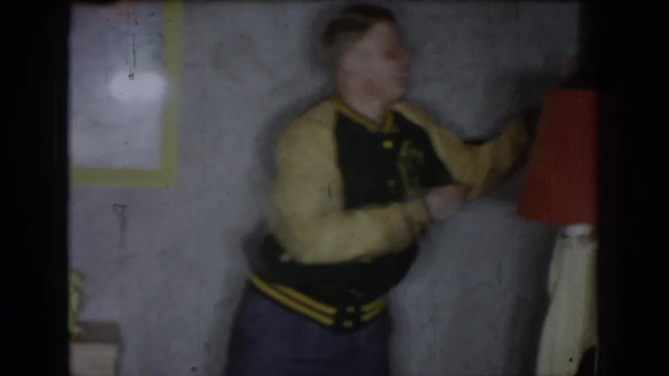 Motion-blurred figure in what appears to be a varsity-style jacket, opening frame of 8mm home movie, circa 1965, Saint Louis, Missouri.