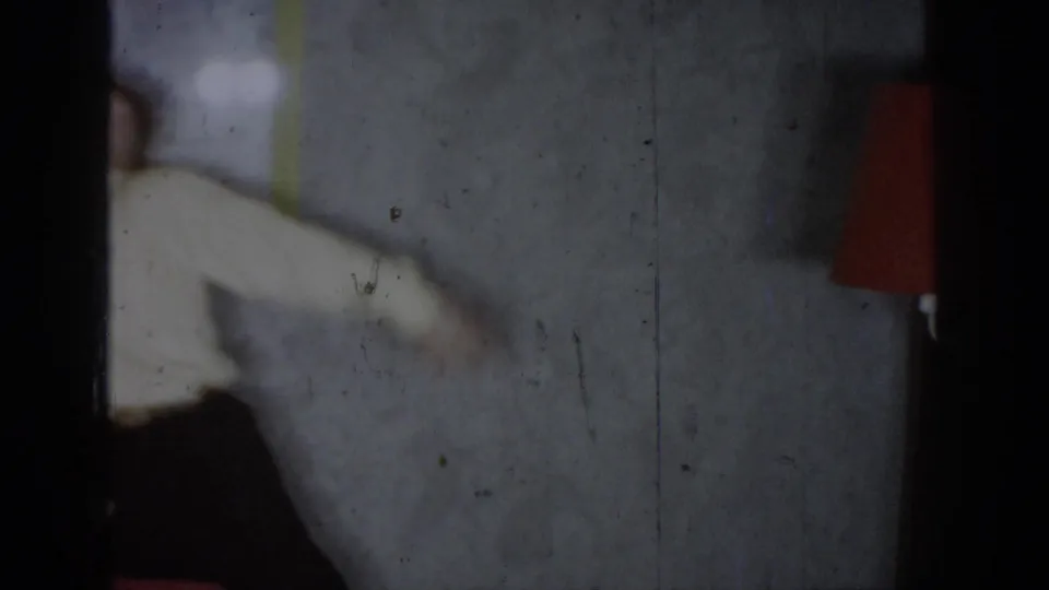 Person in white jacket with arm outstretched, transitional frame from 8mm home movie, circa 1965, Saint Louis, Missouri.