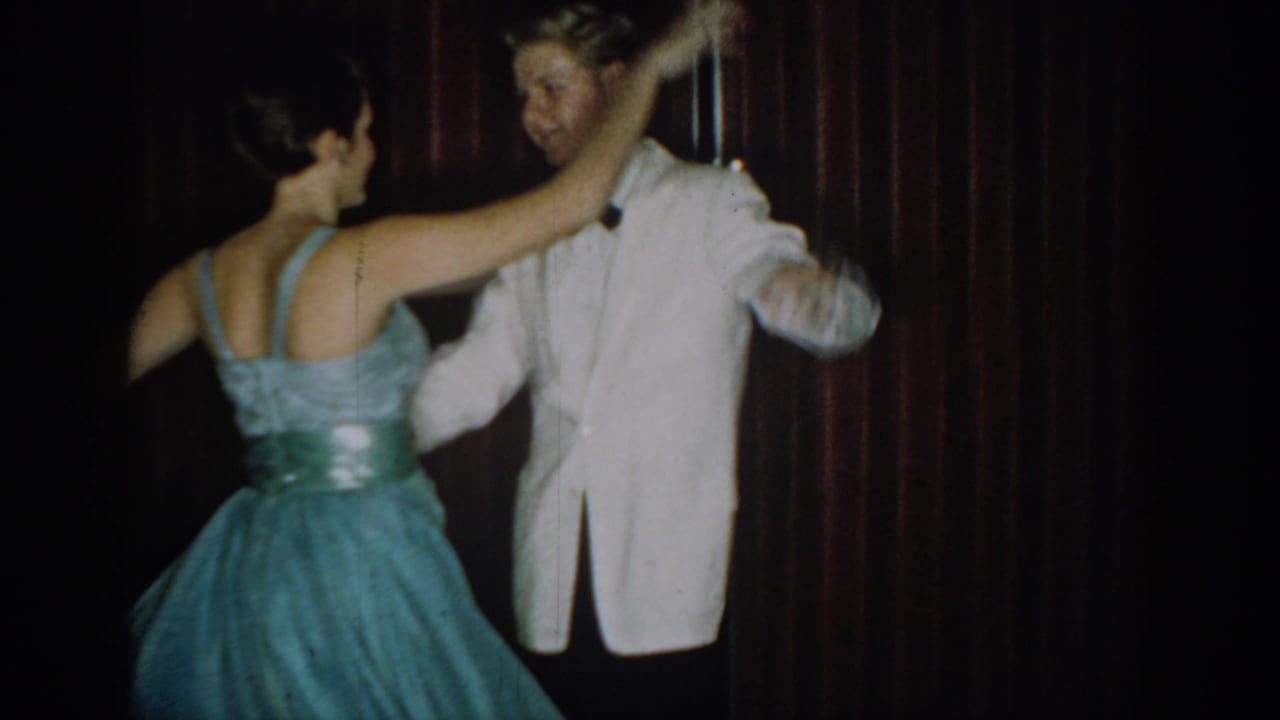 Young couple dancing at a mid-1960s formal party in Saint Louis, Missouri; woman in light blue strapless gown with silver sash, man in white dinner jacket.