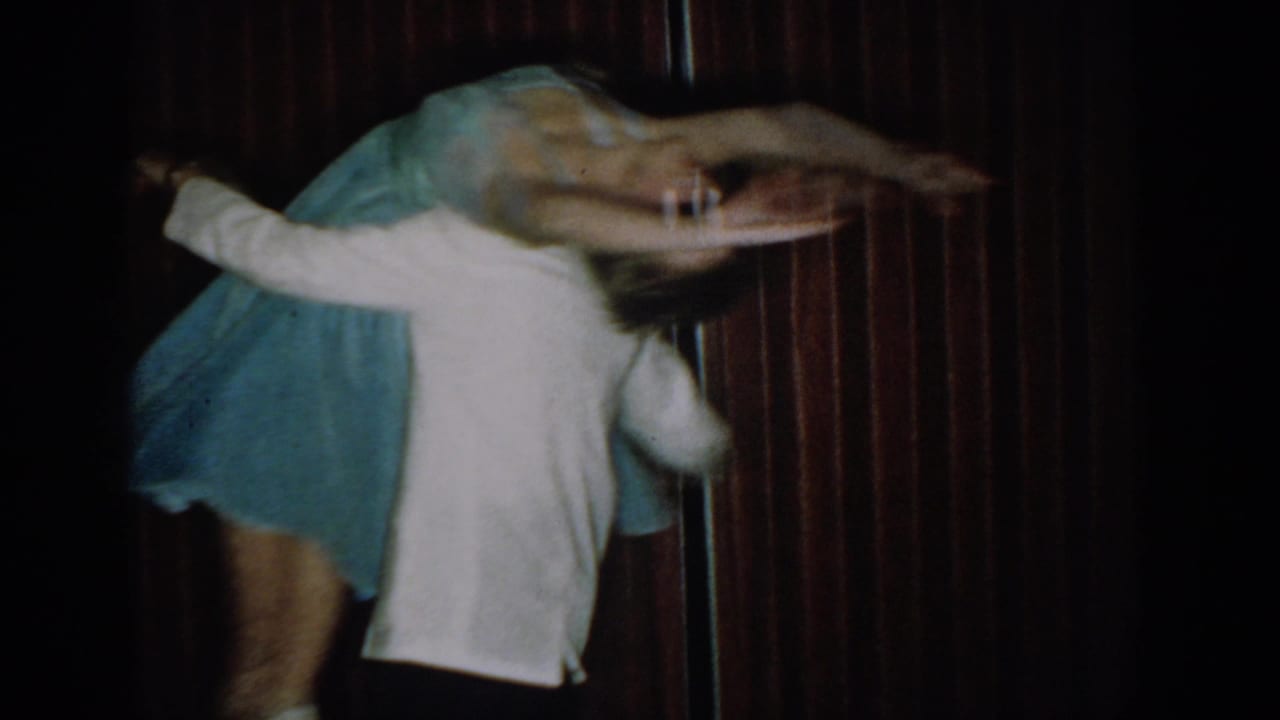 Man and woman in a theatrical arch or dip dance pose against dark red curtain, woman's blue dress visible, consistent with circa 1965 footage.