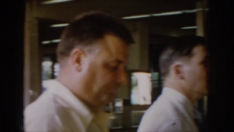 Two men in white shirts appear in close-up profile inside a bar or service area of a mid-1960s restaurant, possibly Saint Louis, Missouri.