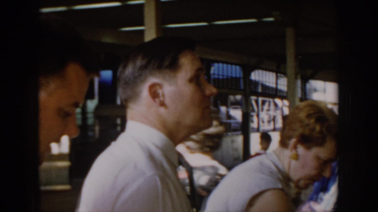 Adult man in white shirt in profile at a covered indoor market in Saint Louis, Missouri, circa 1965; woman in sleeveless top and diffuse daylight through windows behind him.