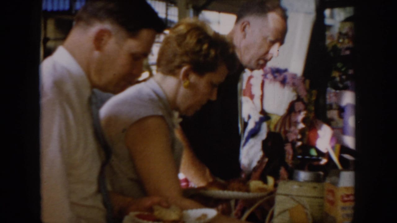 A man and woman lean over a market counter examining goods; colorful packaged items visible at the right edge of the stall.