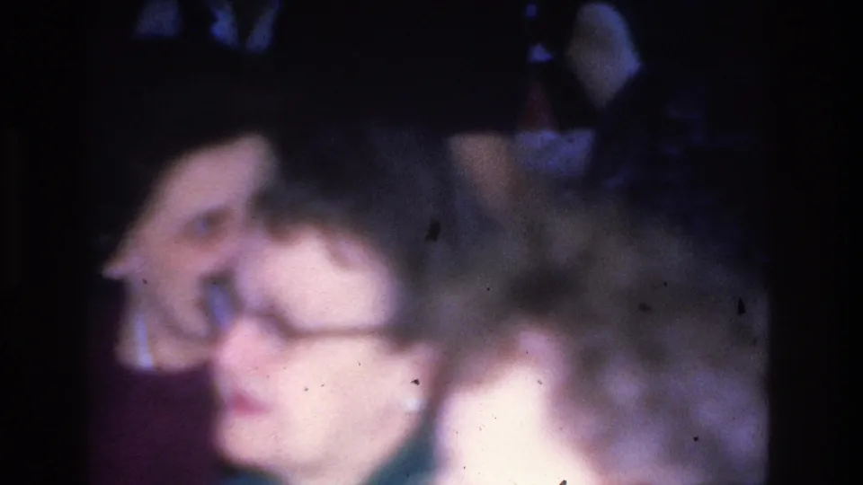 Close-up of two women at an indoor social event in Hoboken, New Jersey, circa 1966, on 8mm film with characteristic blue color shift and soft focus.