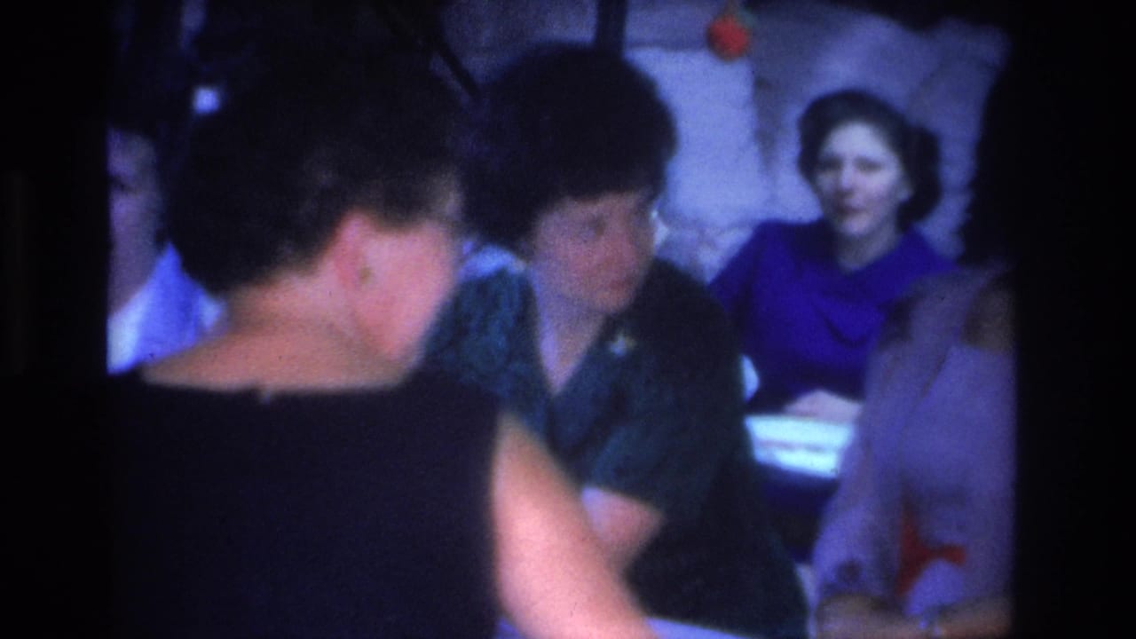Group of women in mid-1960s dress gathered at a table during an evening social event, Hoboken, New Jersey, circa 1966, shot on 8mm film.