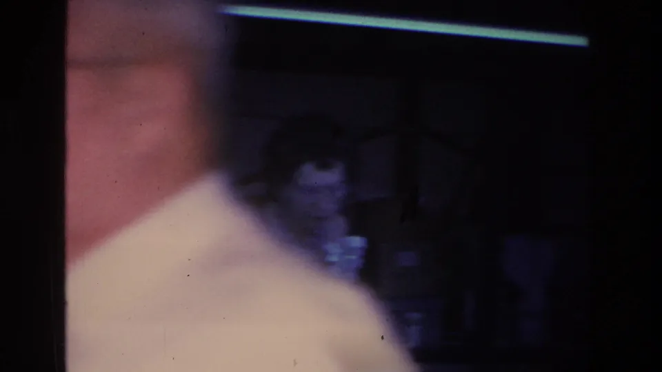 Opening frame of a 1966 Hoboken home movie, heavily underexposed, showing a figure in a light shirt in extreme close foreground.
