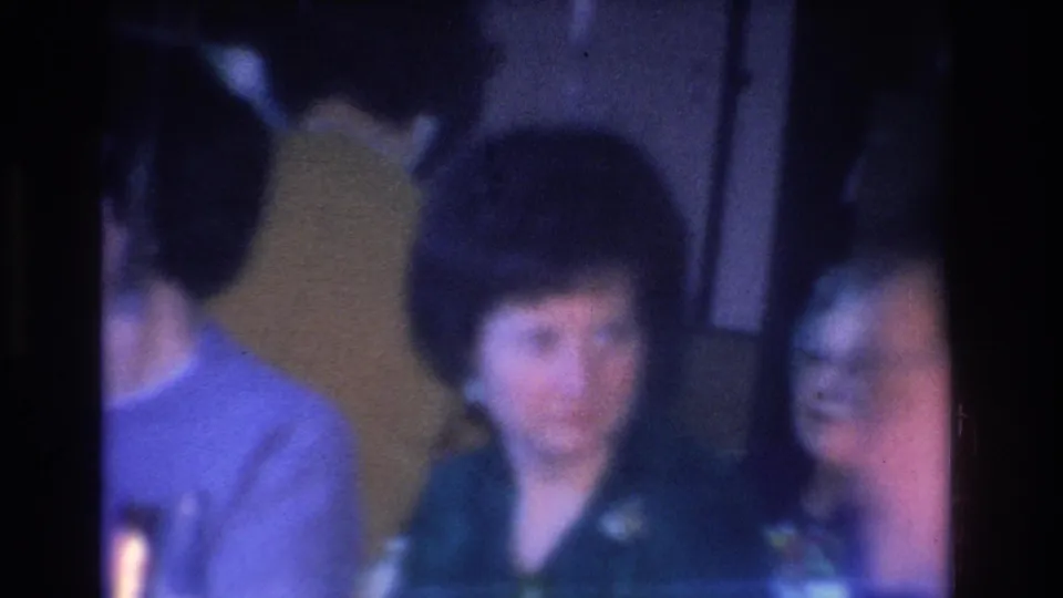 Adult women in casual 1960s attire in a dimly lit interior on 8mm film with blue-purple shift; Hoboken, New Jersey, circa 1966.
