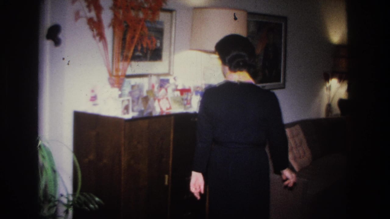 Woman in black dress seen from behind walking toward a dark wood sideboard in a mid-century living room.