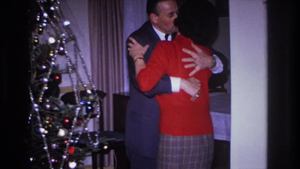 The suited man appears to kiss or lean close to the woman as they embrace near the Christmas tree in Hoboken.