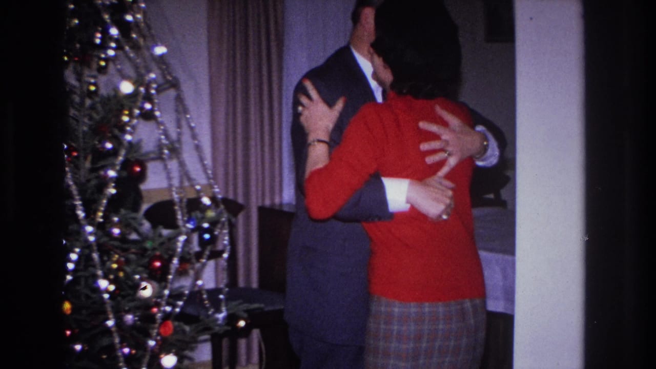 Couple embracing beside a tinsel-and-ornament Christmas tree in a home interior, Hoboken, New Jersey, circa 1966, captured on 8mm color film.