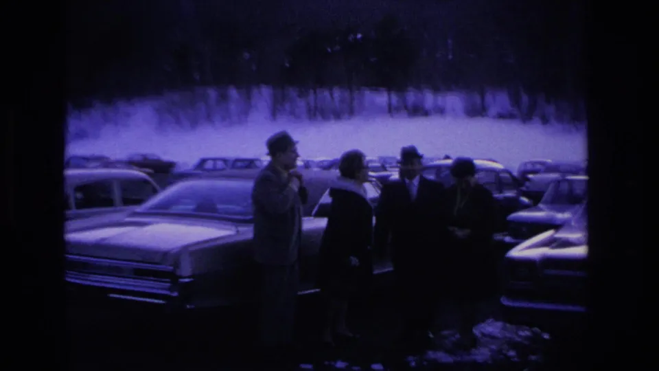 End-of-clip frame with silhouetted figures in a parking lot; darker exposure and increased grain suggest camera movement or end of reel, circa 1966 Hoboken, New Jersey.