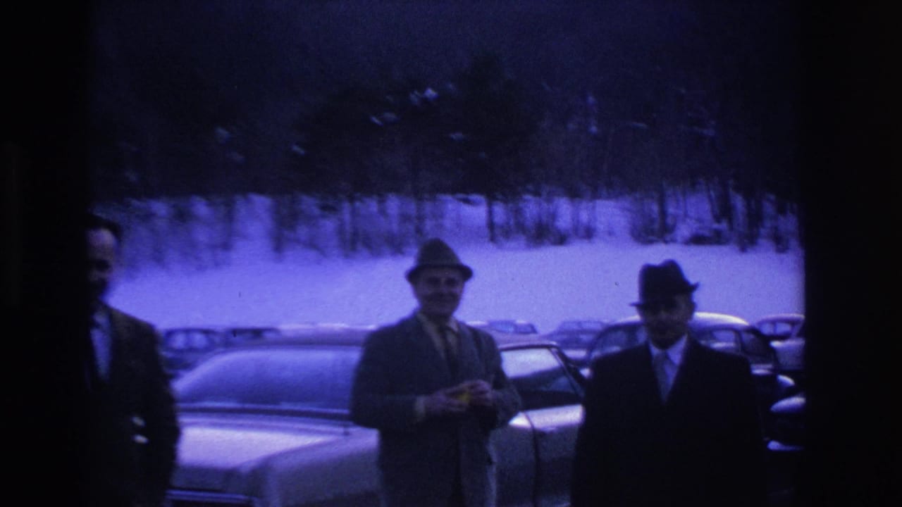 Three men in suits and fedoras stand in a snowy parking lot, Hoboken New Jersey area circa 1966, with classic American sedans visible behind them.