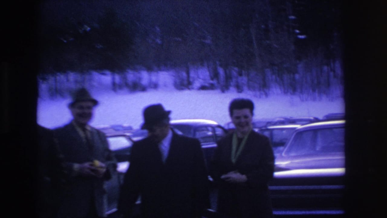 Three men in dark suits and fedoras in a snow-covered parking lot, Hoboken NJ, 1966; blue-purple color cast from aged 8mm film.