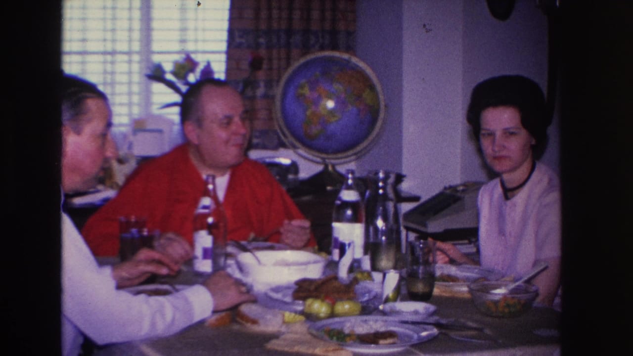 Three adults — two men and a woman — eating at a set dining table in a 1966 Hoboken, New Jersey home interior, with a decorative globe on a stand behind them.