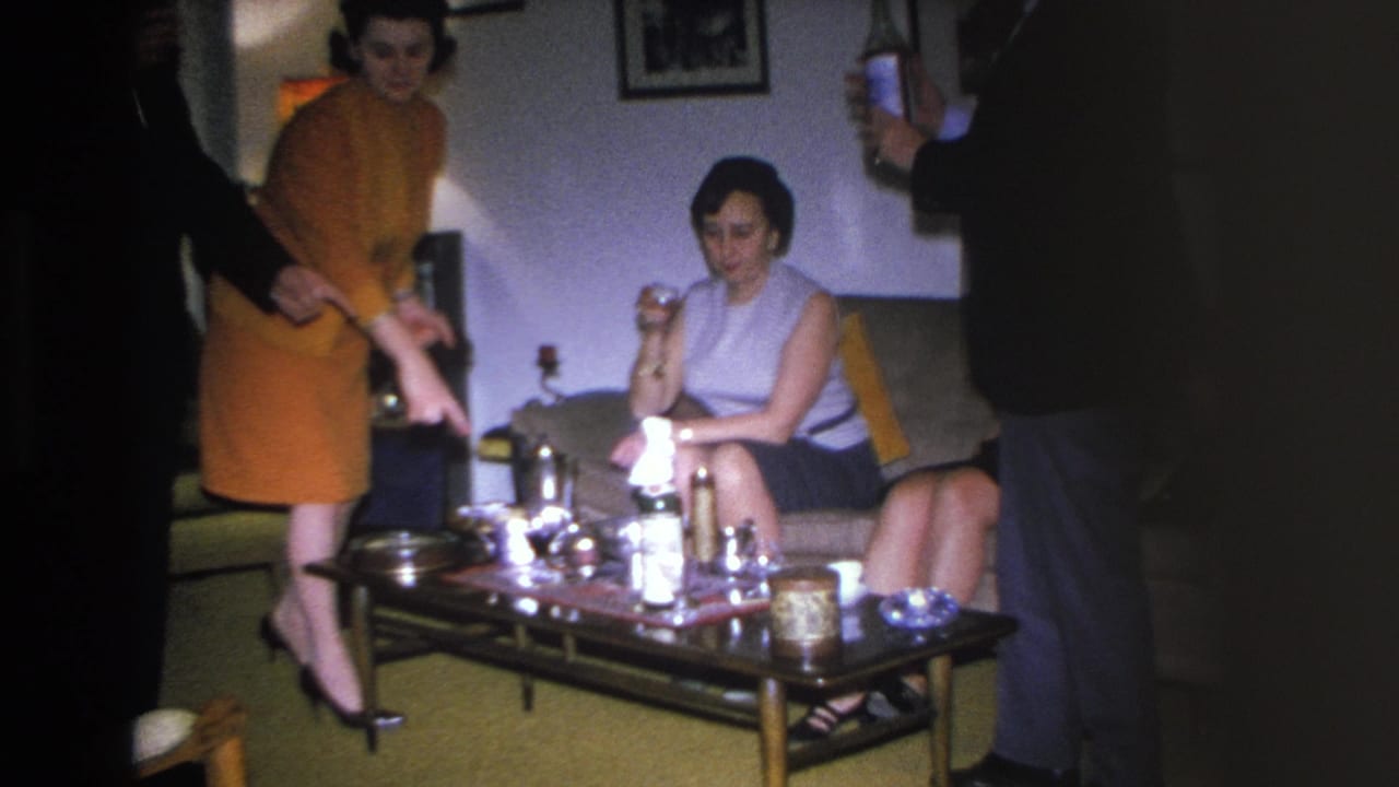 1966 Hoboken home movie: two women at a mid-century living room party, coffee table laden with bottles and glasses.