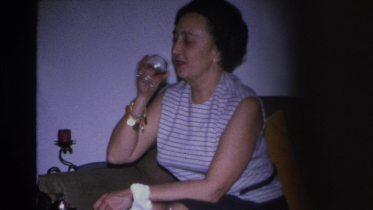 Woman in striped top raising a glass near her face; gold bracelet and earring visible, wall-mounted candle sconce behind her.