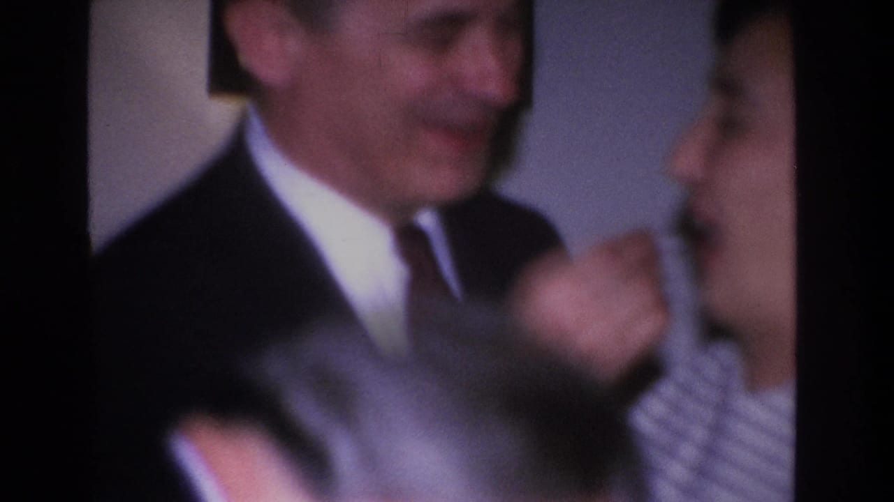 Motion-blurred opening frame of a 1966 8mm home movie showing a couple indoors, attributed to Hoboken, New Jersey.