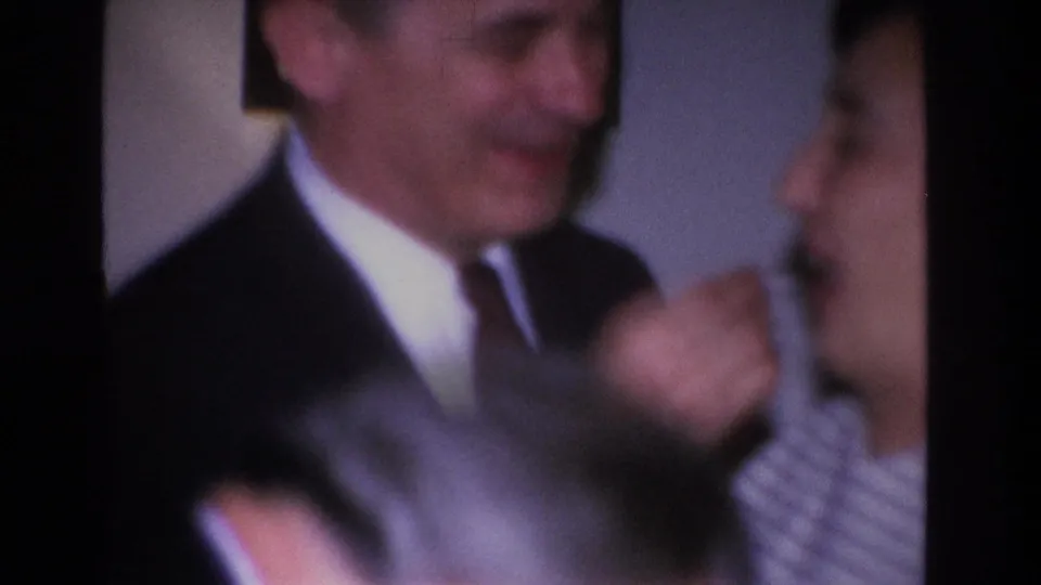 Motion-blurred opening frame of a 1966 8mm home movie showing a couple indoors, attributed to Hoboken, New Jersey.