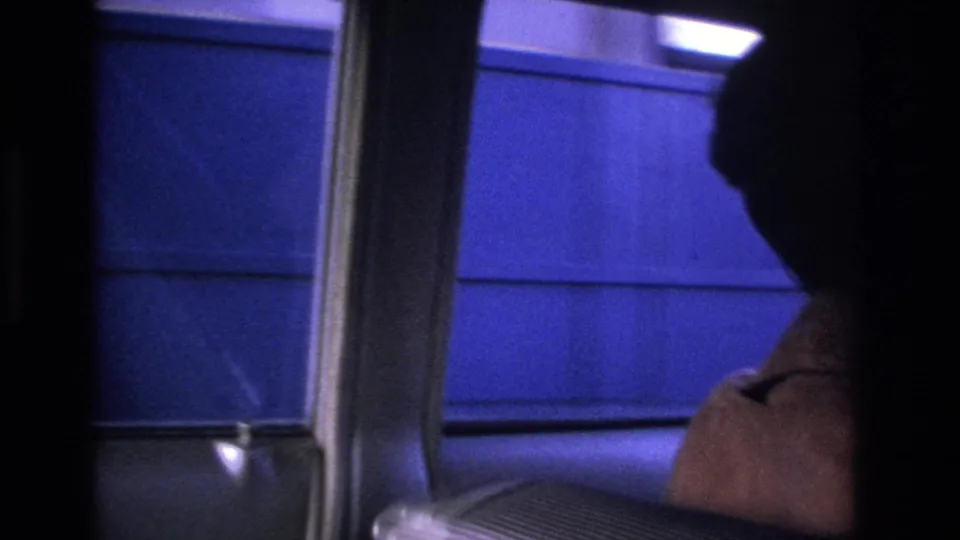8mm footage of a blue toll booth structure from inside a passing car, Hoboken New Jersey area, c. 1966; driver's silhouette at frame right.