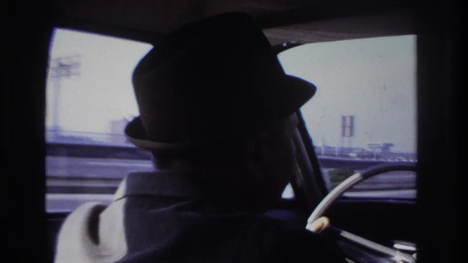 Final frame of the 1966 Hoboken driving clip, with the fedora-wearing driver silhouetted inside the moving car.