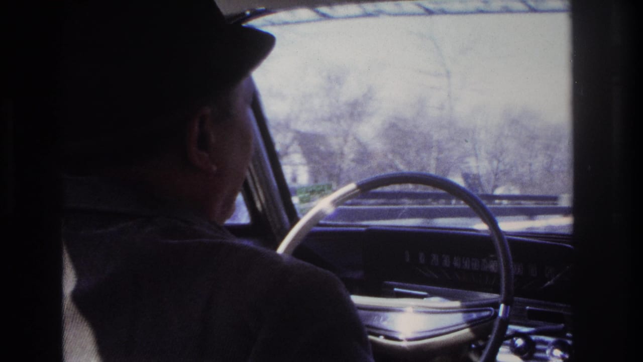 Shadowed 1966 Hoboken car-interior frame showing the driver in profile beside the steering wheel and windshield view.