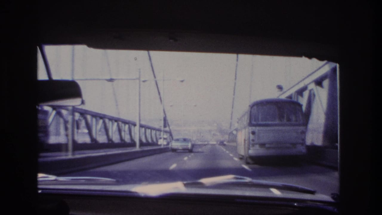 1966 Hoboken-area 8mm view through a car windshield as traffic and a bus travel across a steel bridge.